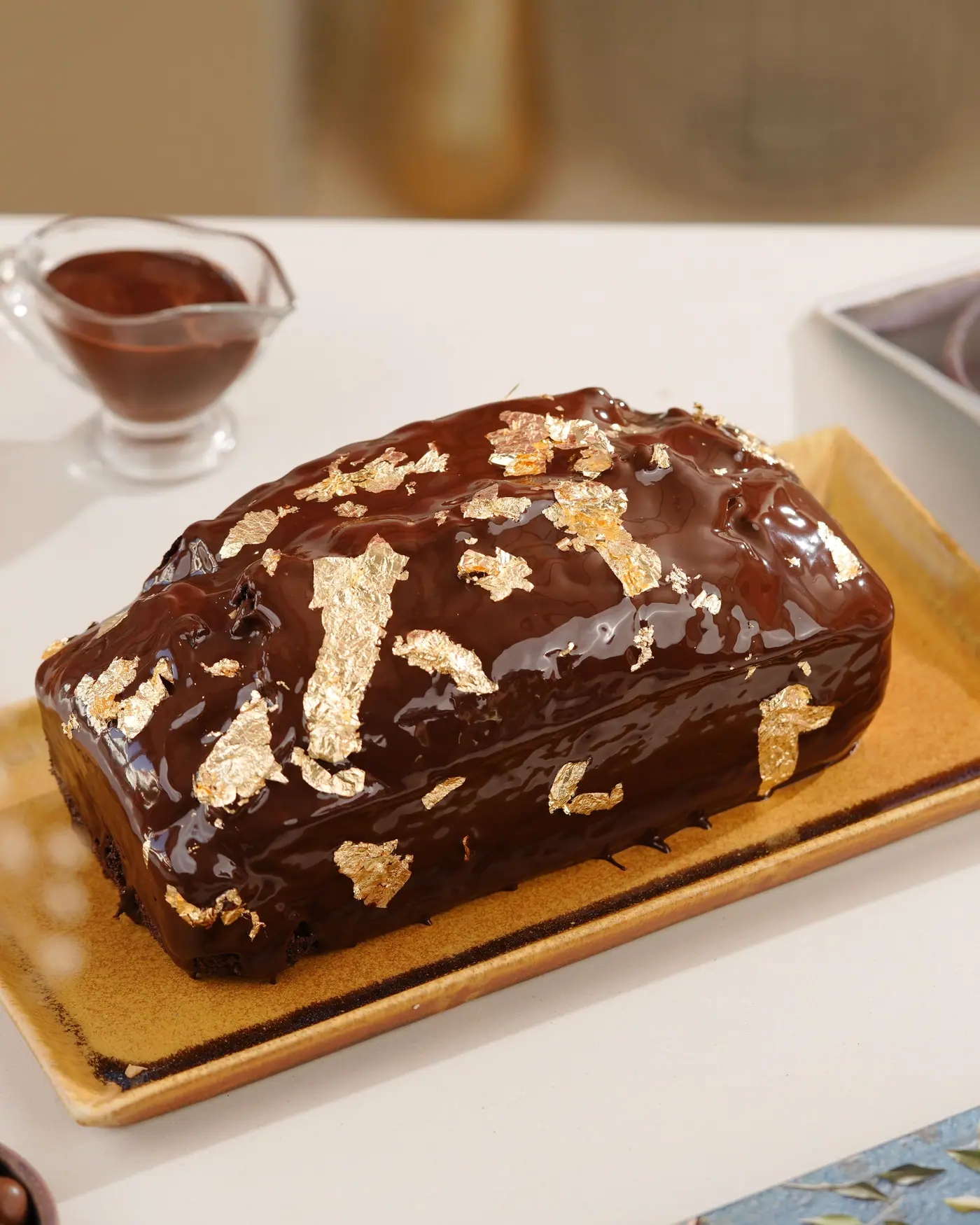Chocolate tea cake with a glossy glaze and gold leaf